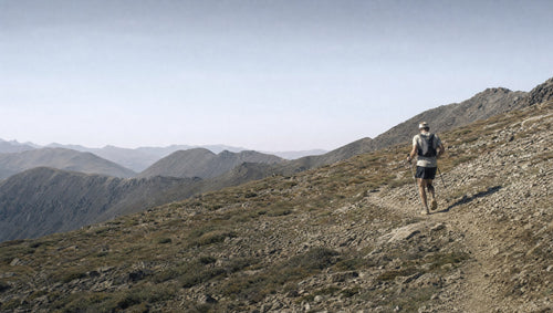 Trail runner high on an exposed ridgeline above treeline